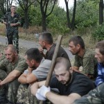 Prisoners-of-war, who are Ukrainian servicemen captured by pro-Russian separatists, sit on the ground as they are assigned to clean a street in Snizhne (Snezhnoye), Donetsk region